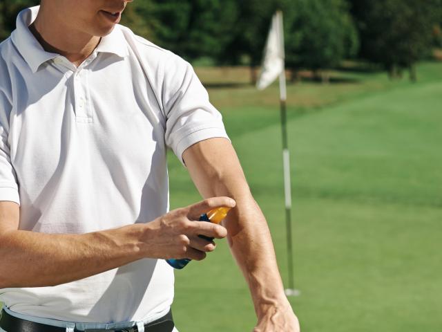 Golfer applying sunscreen