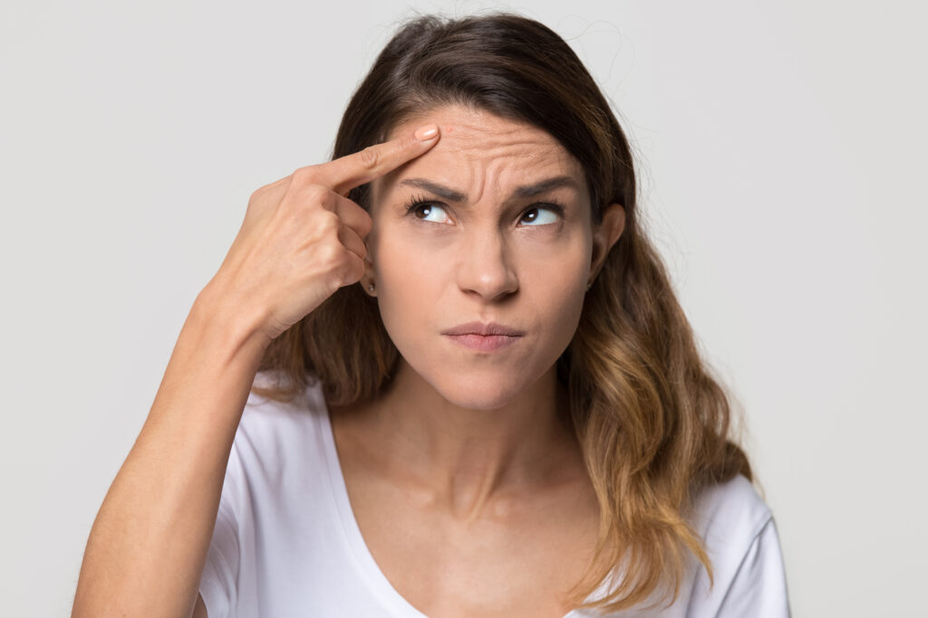 Stressed woman pointing to wrinkles on forehead